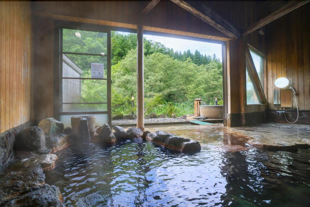 Cette chambre dispose d'une piscine d'eau et d'une grande fenêtre. dans l'établissement Sasakura onsen Ryuunso, à Itoigawa