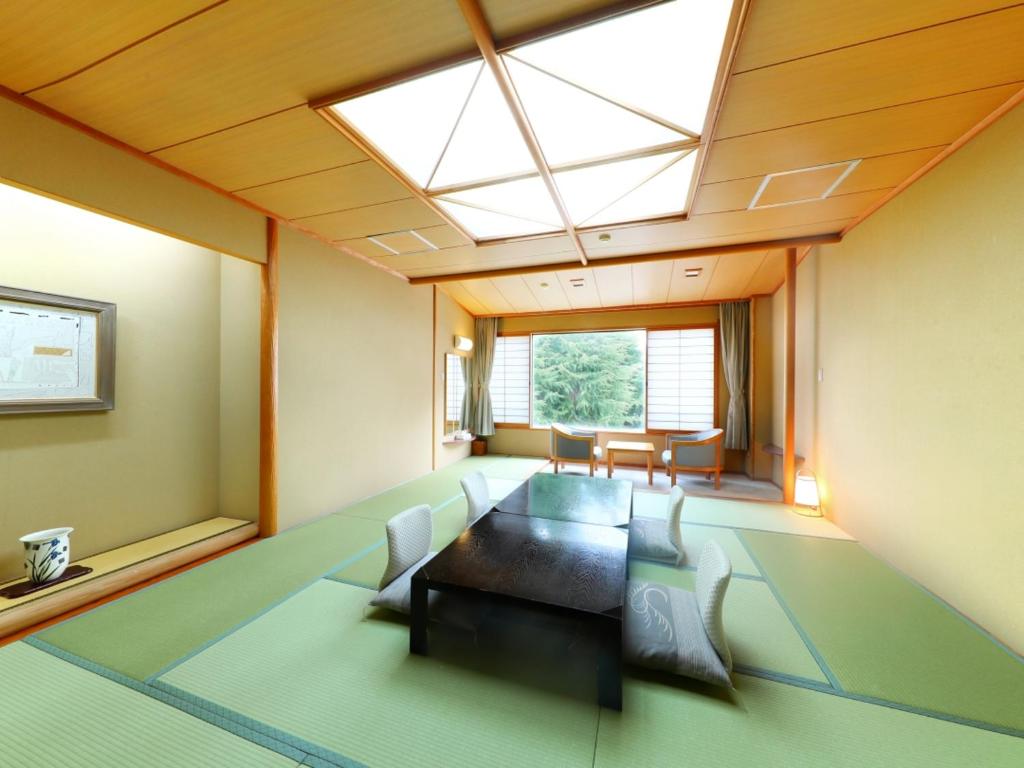 une chambre avec une table, des chaises et une lucarne dans l'établissement Sasakura onsen Ryuunso, à Itoigawa