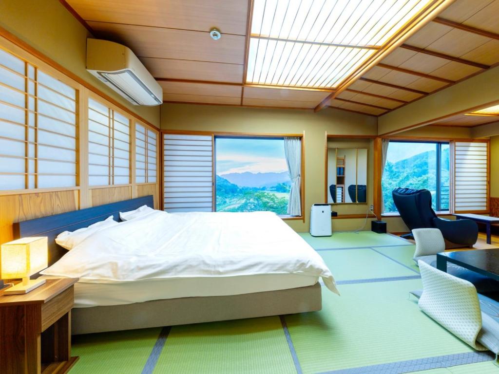 une chambre avec un lit dans une pièce avec des fenêtres dans l'établissement Sasakura onsen Ryuunso, à Itoigawa