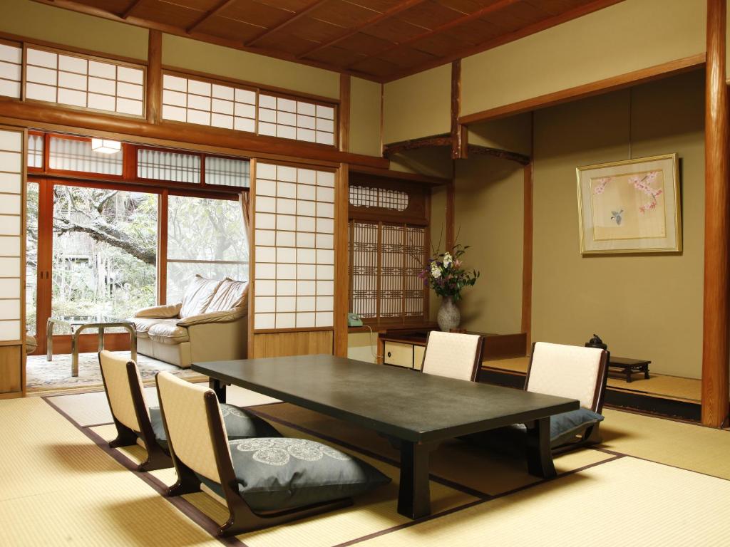 une salle à manger avec une table et des chaises noires dans l'établissement Hashinoya Bekkan Ransui, à Kobe