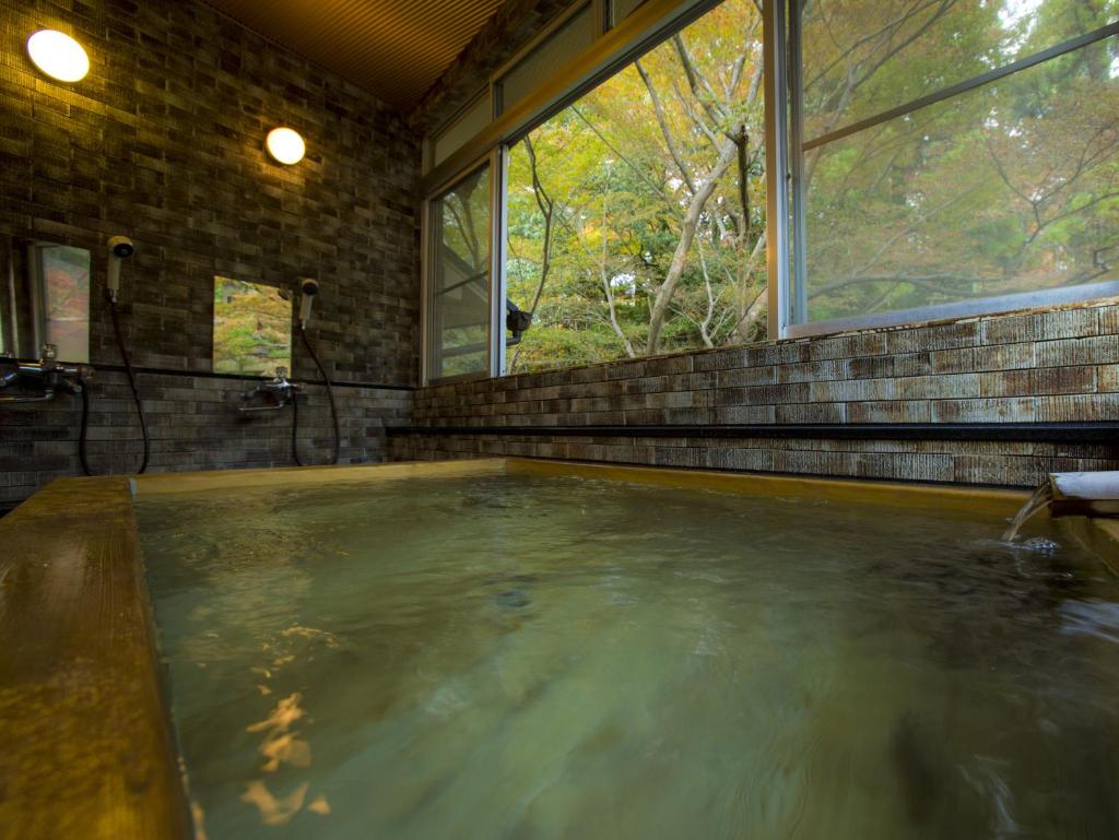 une baignoire jacuzzi dans une chambre avec fenêtre dans l'établissement Hashinoya Bekkan Ransui, à Kobe