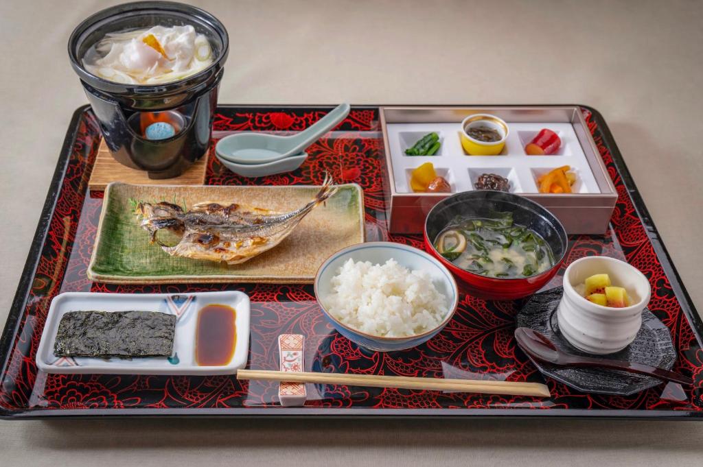 un plateau de nourriture sur une table avec du riz et des baguettes dans l'établissement 熱海温泉 法悦 旅館, à Atami