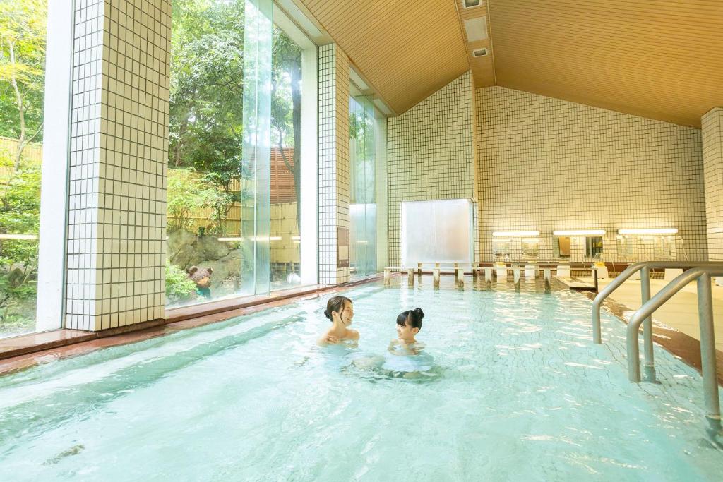 - deux femmes dans une piscine dans l'établissement Ooedo Onsen Monogatari Awazu Grand Hotel, à Komatsu