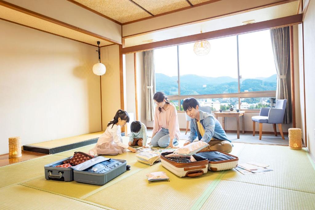 un groupe de personnes assises par terre avec des bagages dans l'établissement Ooedo Onsen Monogatari Ureshinokan, à Ureshino