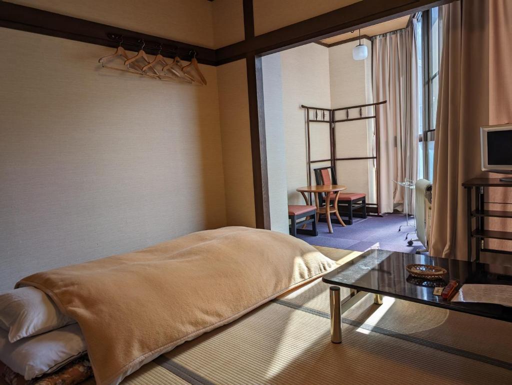 une chambre avec un lit et une table dans une pièce dans l'établissement Oyado Nozawaya, à Nozawa Onsen