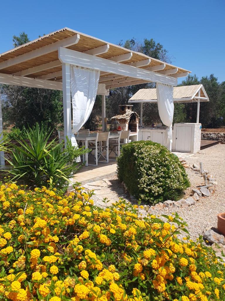 un patio avec une pergola blanche et des fleurs jaunes dans l'établissement Villa Venus, A Countryside Retreat, à San Vito dei Normanni