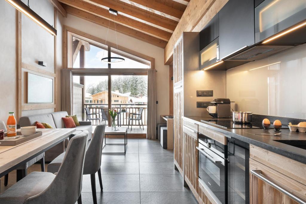 une cuisine avec un comptoir et une table avec des chaises dans l'établissement MGM Hôtels & Résidences - Résidence Le Hameau de l'Ours, à Manigod 59 autres photos