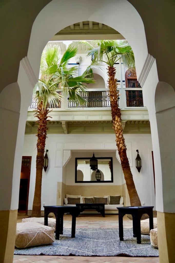 deux palmiers dans un salon avec une table dans l'établissement Riad Tzarra, à Marrakech
