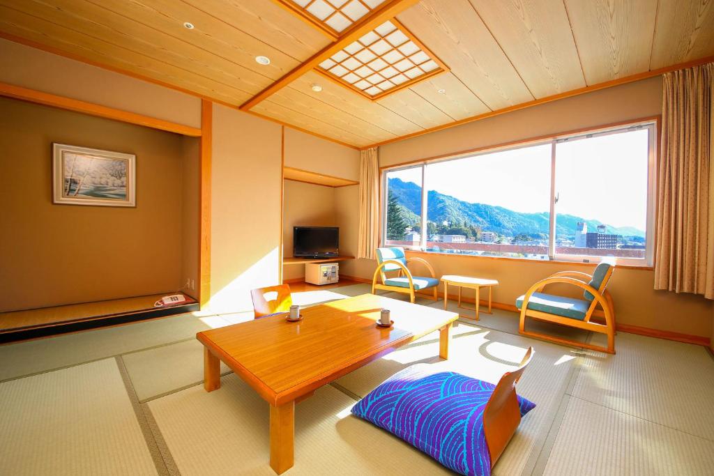 un salon avec une table et une grande fenêtre dans l'établissement Ooedo Onsen Monogatari Hotel Kinugawa Gyoen, à Nikkō