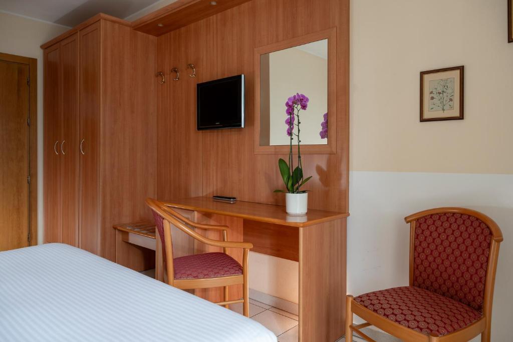 une chambre avec un bureau avec un lit et deux chaises dans l'établissement Hotel Regina, à Gravedona