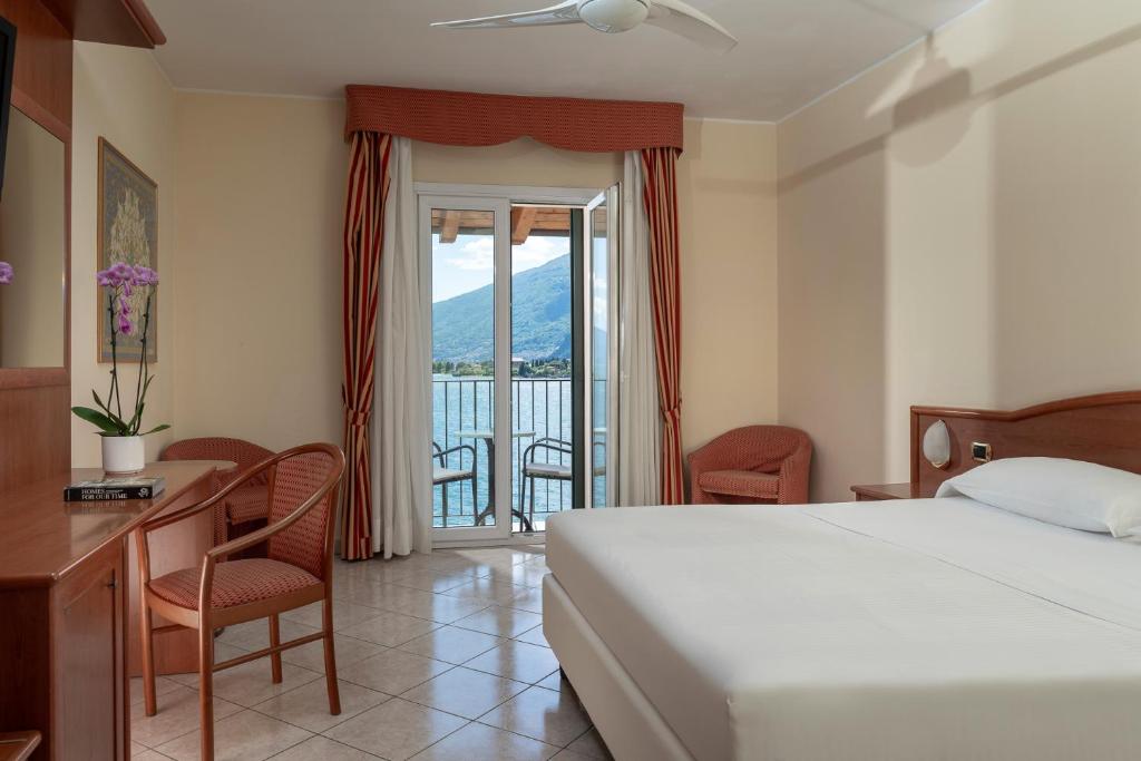 une chambre avec un lit et un bureau et un balcon dans l'établissement Hotel Regina, à Gravedona