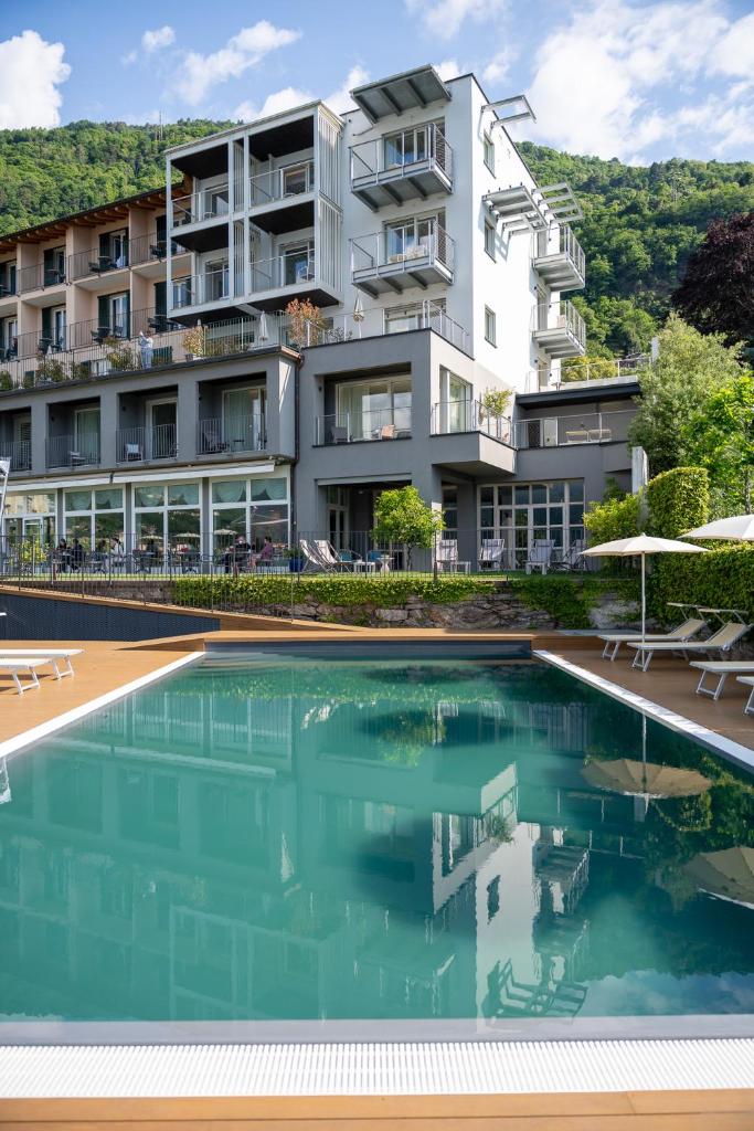 un immeuble d'appartements avec une piscine en face dans l'établissement Hotel Regina, à Gravedona