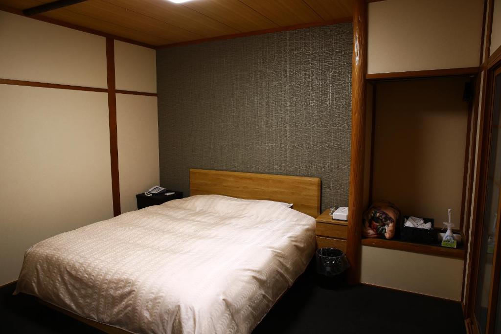 - une chambre avec un lit blanc et une tête de lit en bois dans l'établissement ホテルサルビア, à Tendō