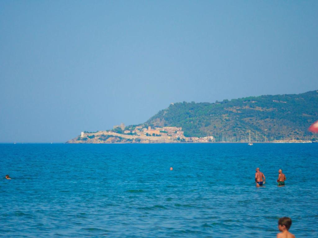 un groupe de personnes dans l'eau à la plage dans l'établissement ISA - Village with swimming pool in Albinia just 150 mt from the sea, à Albinia