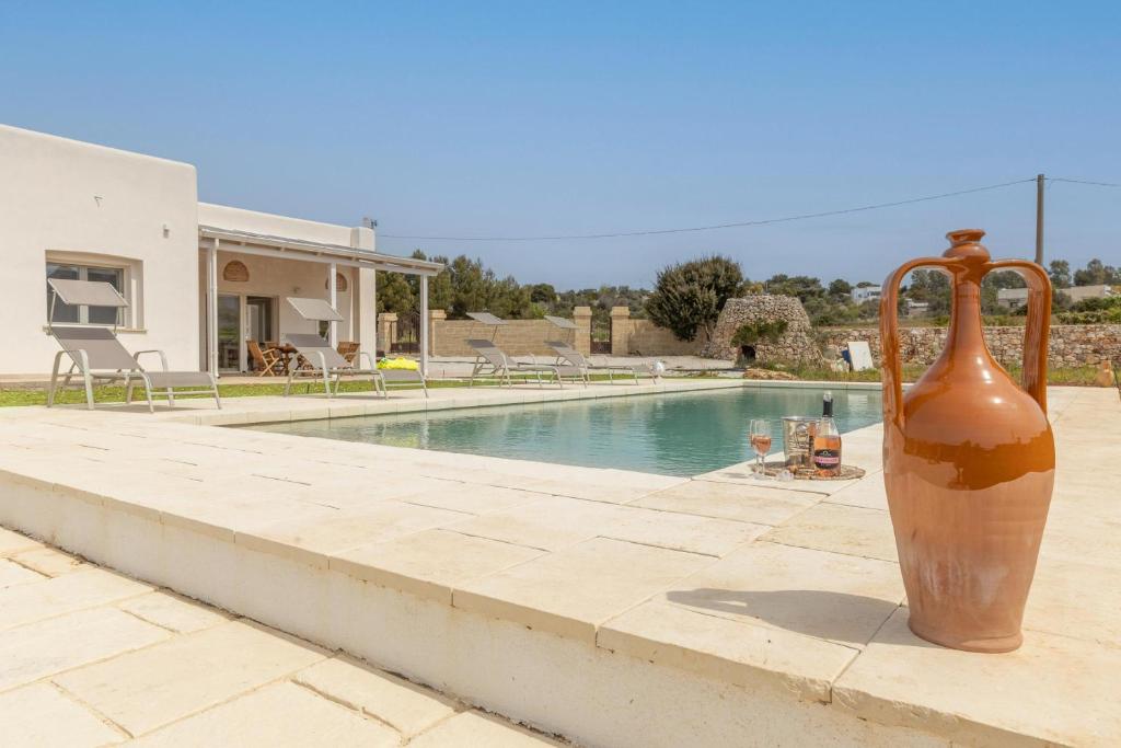 un grand vase assis sur un mur à côté d'une piscine dans l'établissement Villa Incantesimo, à Marina di Pescoluse