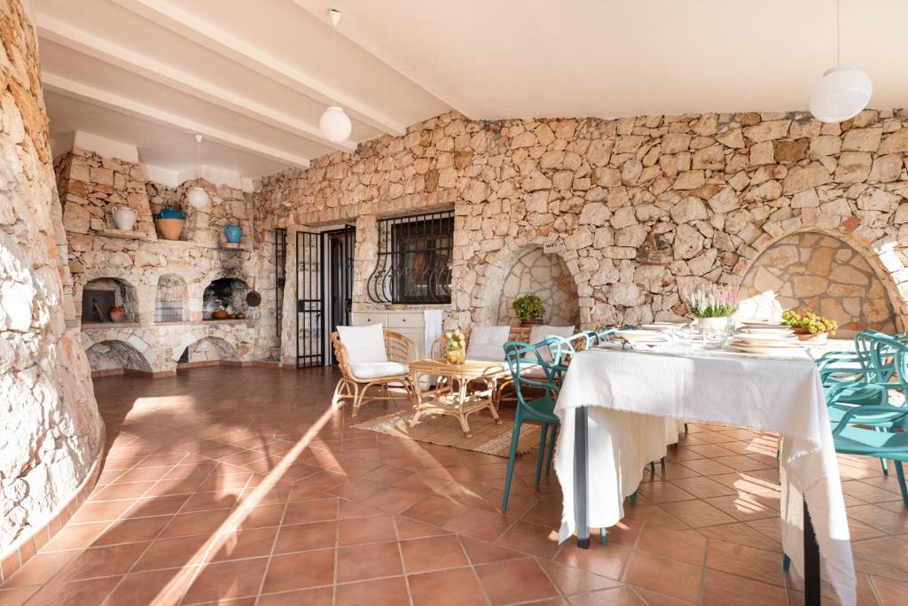 une salle à manger avec une table et un mur en pierre dans l'établissement Villa Li Munti con piscina, à Marina di Leuca
