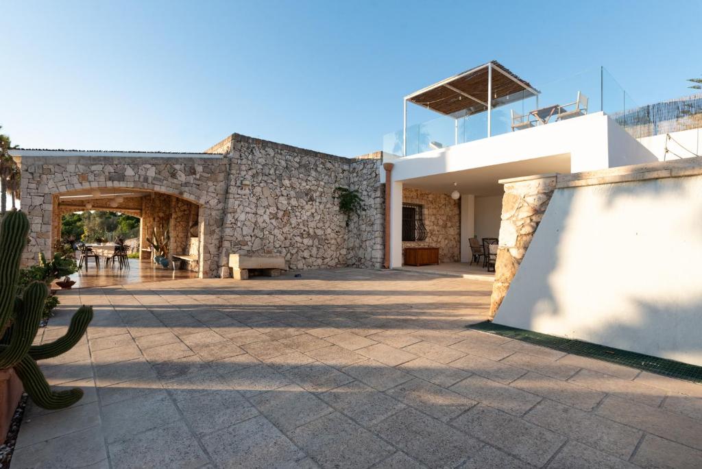 - un bâtiment avec un mur en pierre et une terrasse dans l'établissement Villa Li Munti con piscina, à Marina di Leuca