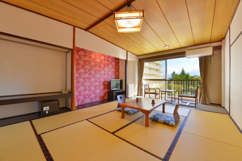 un salon avec une table et un écran dans l'établissement Ooedo Onsen Monogatari Hotel Shinko, à Fuefuki