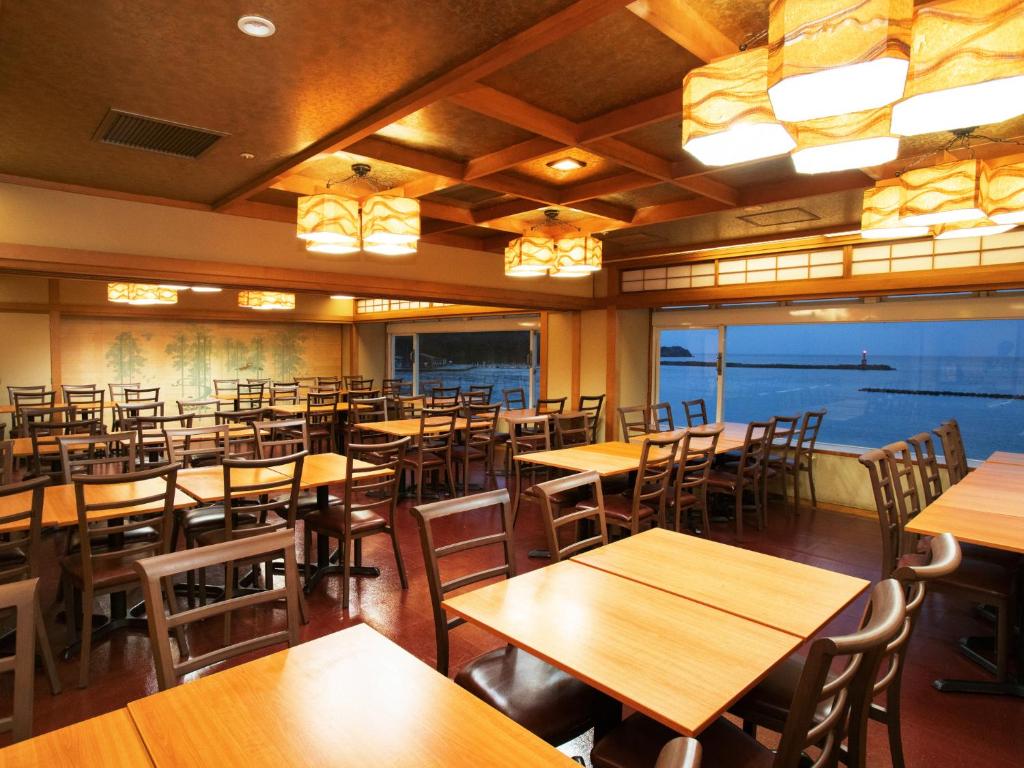 un restaurant vide avec des tables et des chaises en bois dans l'établissement Nishiizu Matsuzaki Itoen Hotel, à Matsuzaki