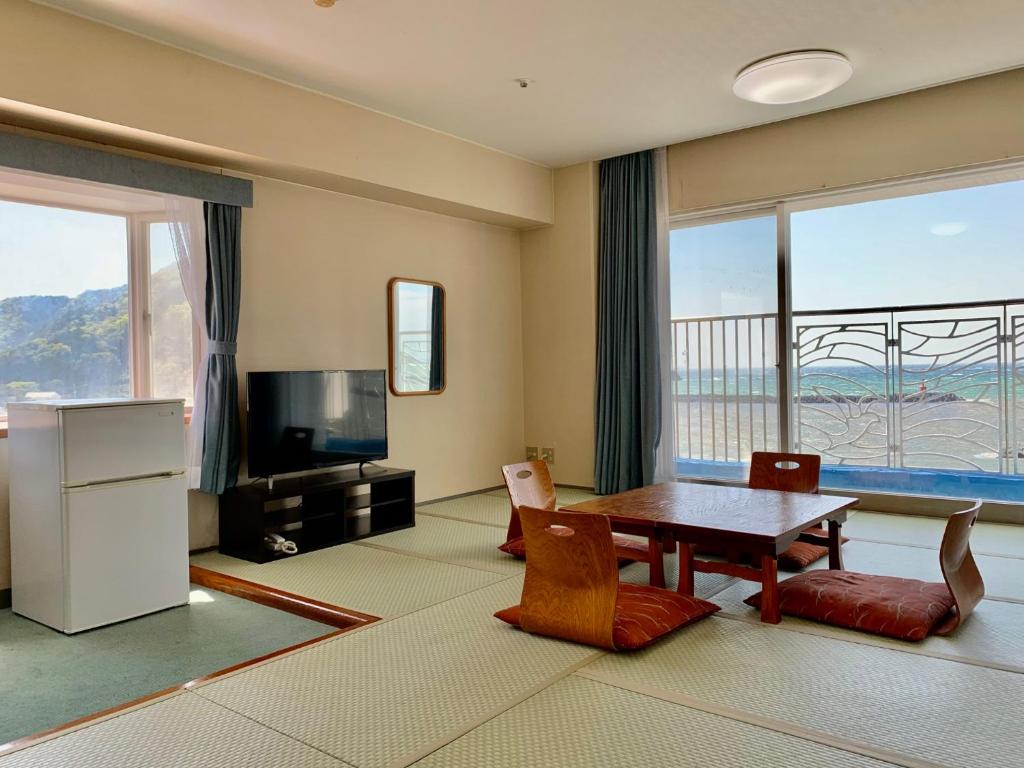 un salon avec une table et une télévision dans l'établissement Nishiizu Matsuzaki Itoen Hotel, à Matsuzaki
