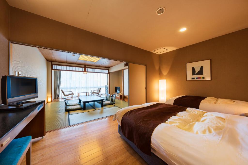une chambre d'hôtel avec un lit et une télévision dans l'établissement Shiragiku, à Beppu