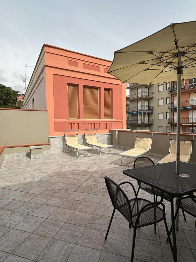 un patio avec une table, des chaises et un parasol dans l'établissement Hotel Delle Rose, à San Bartolomeo al Mare 97 autres photos