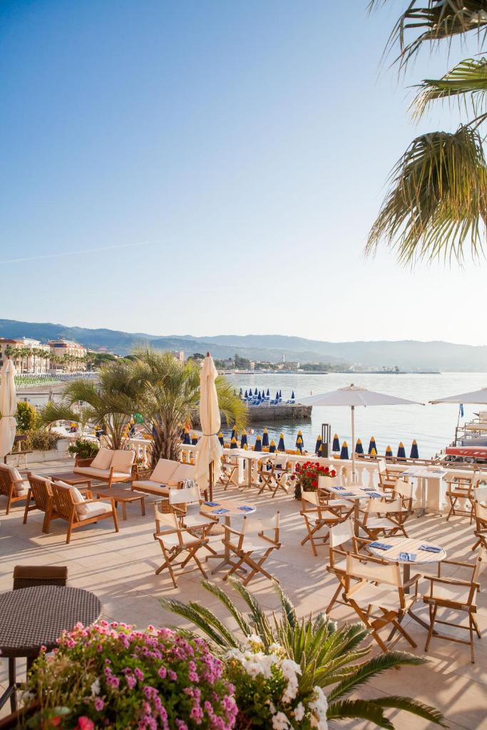 un complexe avec des chaises et des tables et une plage dans l'établissement Hotel Golfo e Palme, à Diano Marina