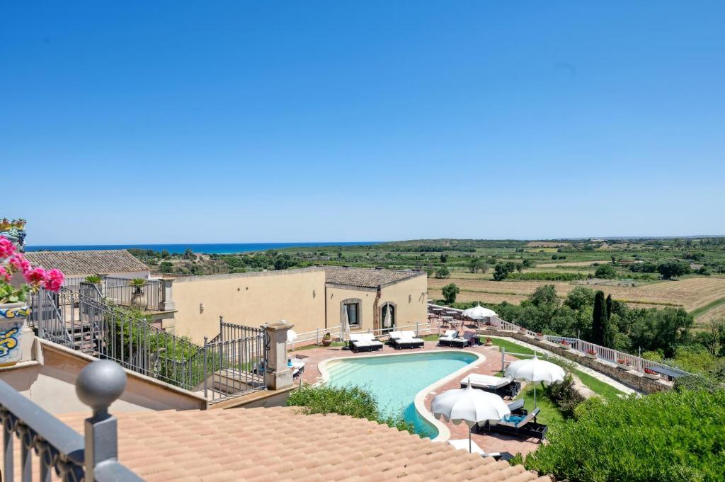 un complexe avec une piscine et des parasols sur un balcon dans l'établissement Hotel La Corte Del Sole, à Noto