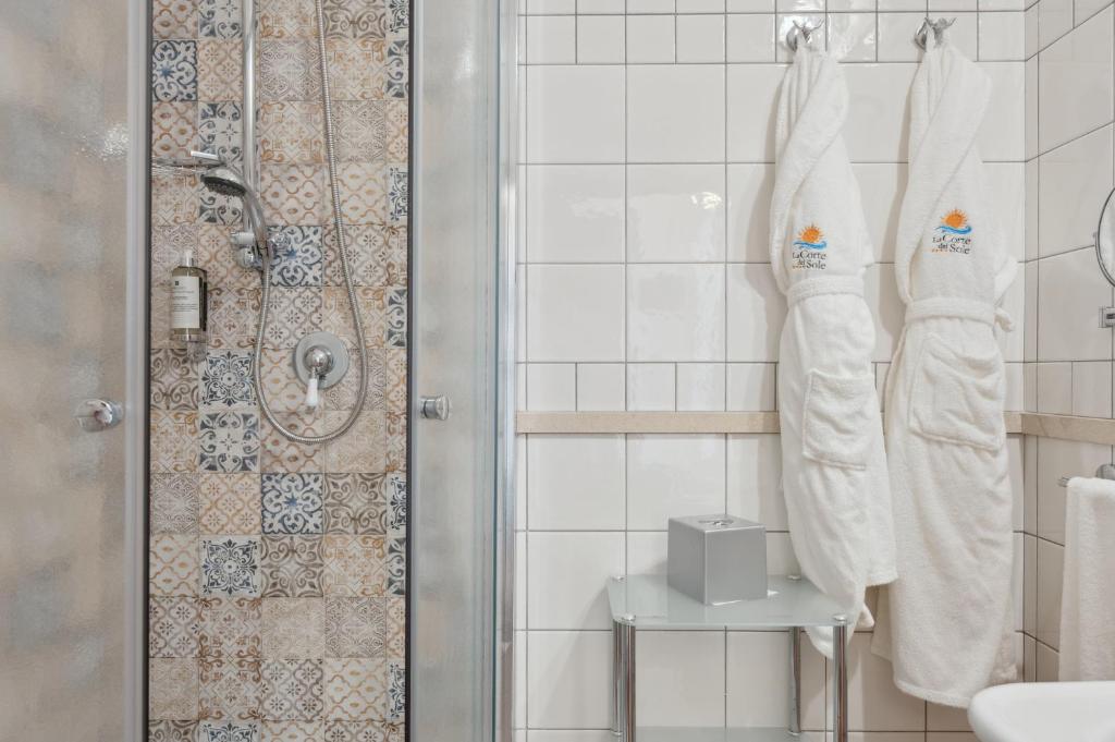 une salle de bain avec des serviettes blanches et une douche dans l'établissement Hotel La Corte Del Sole, à Noto