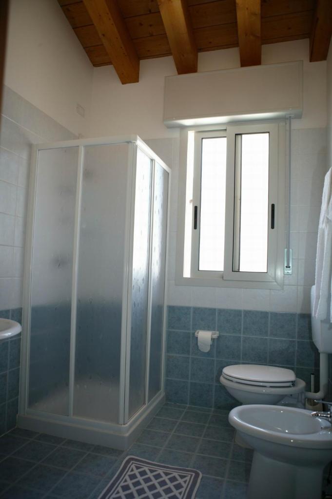 une salle de bain avec douche et toilettes et une fenêtre dans l'établissement Hotel Ca' D'Oro, à Caorle