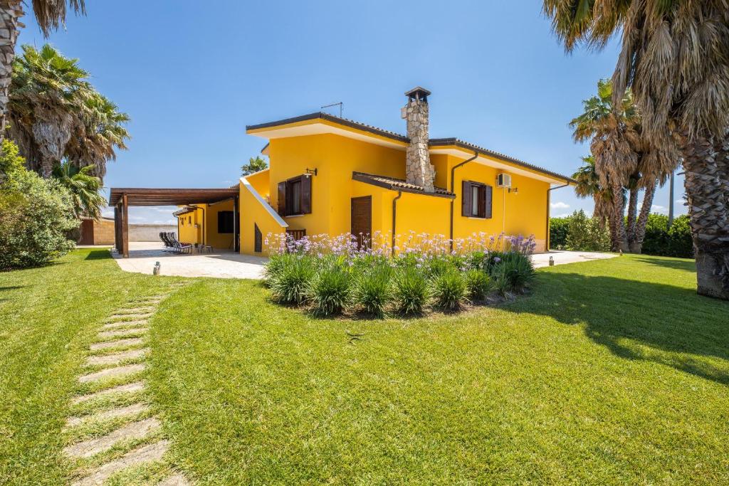 une maison jaune avec des palmiers et une cour dans l'établissement Villa Esmeralda, à Taviano