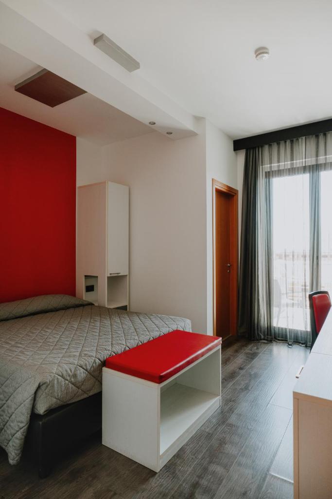 une chambre avec un lit avec un mur rouge dans l'établissement Eden Hotel, à San Salvo