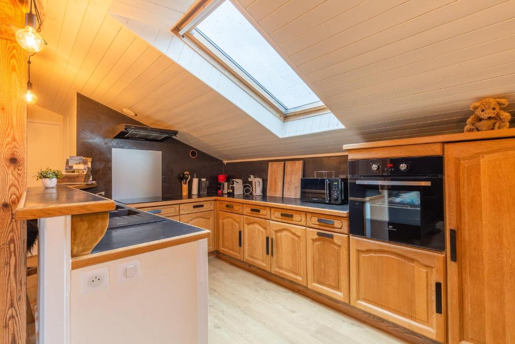 une cuisine avec des armoires en bois et un puits de lumière dans l'établissement Cozy apartment in the village center, à Saint-Jean-de-Sixt