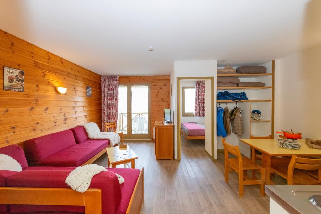 un salon avec un canapé rouge et une table dans l'établissement Résidence Capfun Couleurs Soleil, Oz en Oisans, à Oz