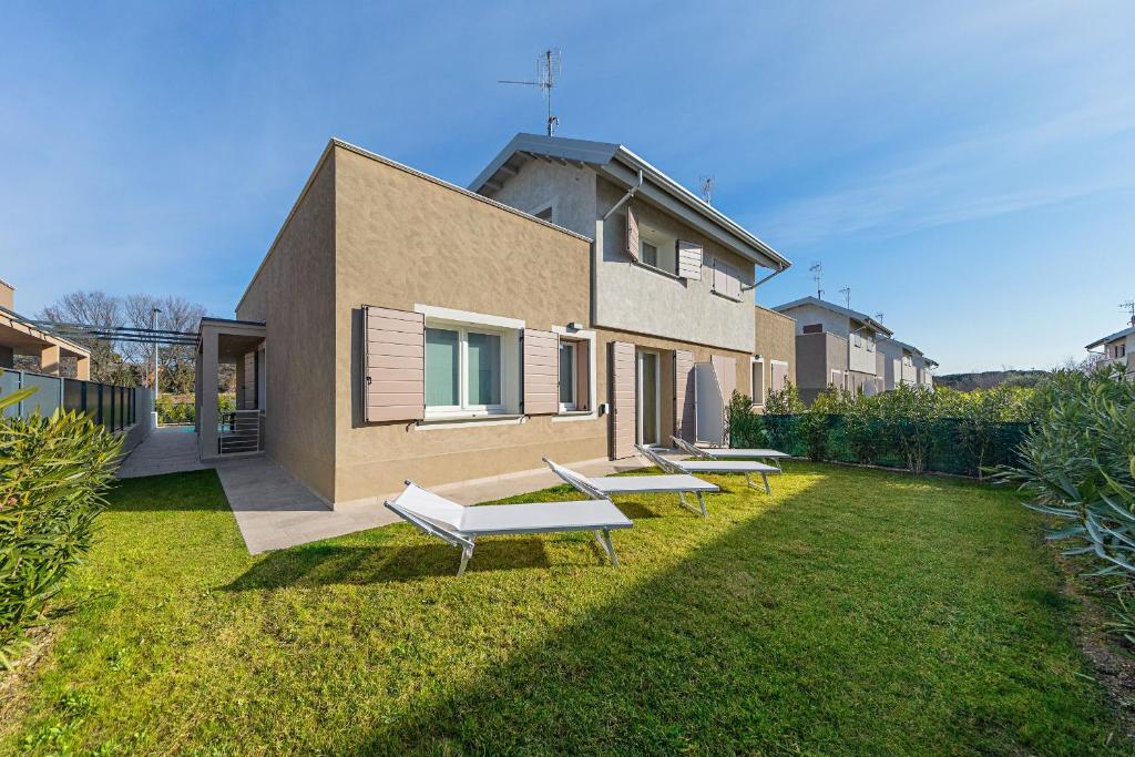 un groupe de bancs assis dans l'herbe devant une maison dans l'établissement Villa Prestige, à Sirmione