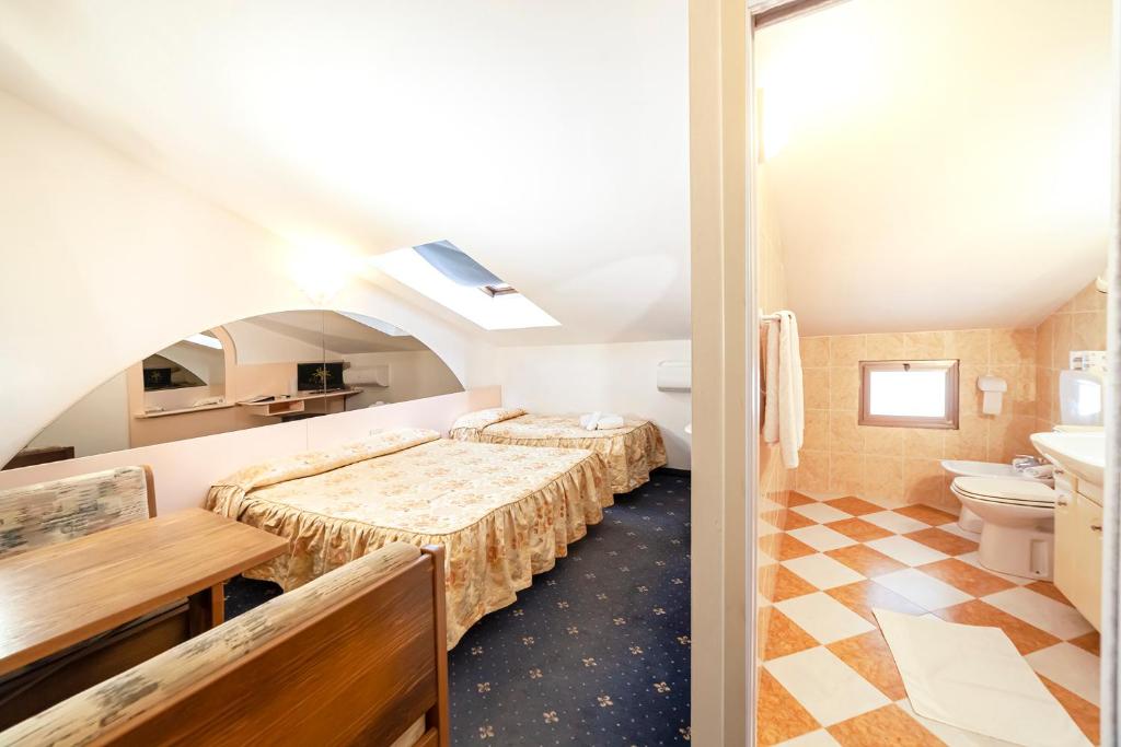 une chambre d'hôtel avec deux lits et une salle de bain dans l'établissement Hotel Villa Luisa, à Lignano Sabbiadoro