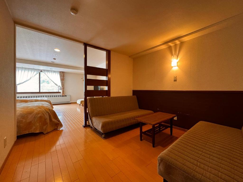 une chambre avec un lit, un canapé et une fenêtre dans l'établissement Kidoike Onsen Hotel, à Yamanouchi 63 autres photos