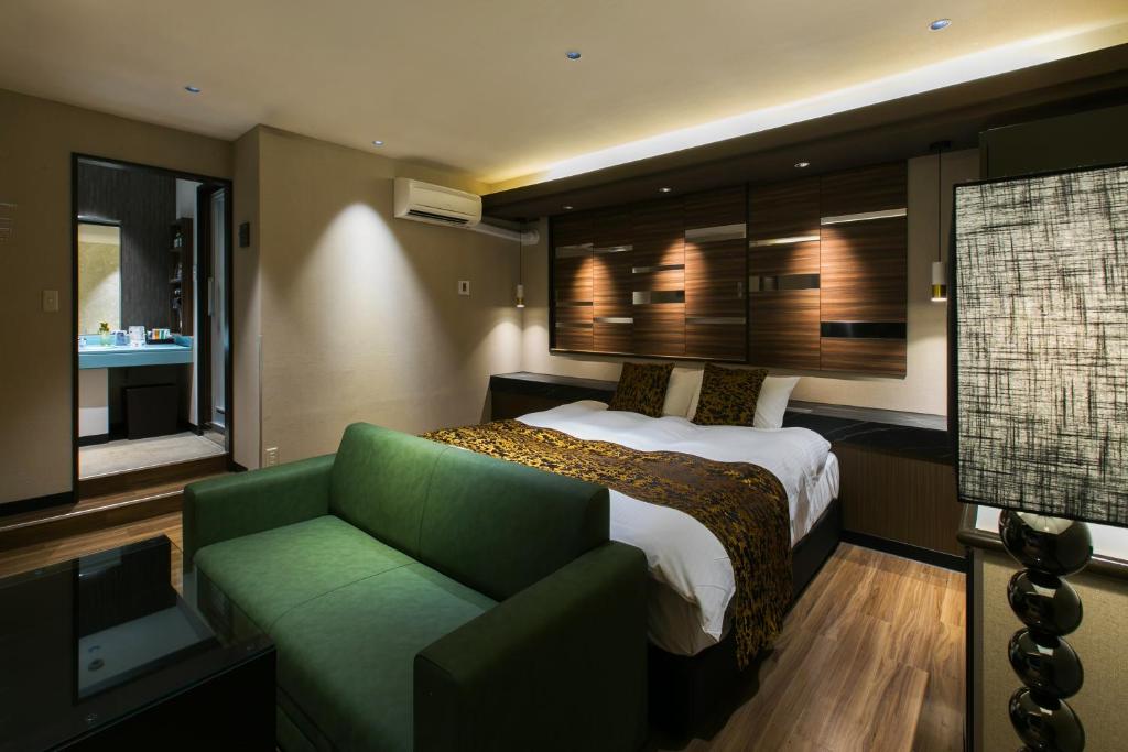 une chambre d'hôtel avec un lit et un canapé vert dans l'établissement HOTEL Luana, à Kitakyūshū