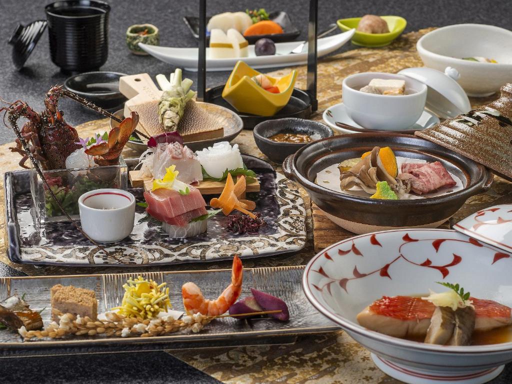 une table avec des assiettes et des bols de nourriture dans l'établissement Shimoda Central Hotel, à Shimoda