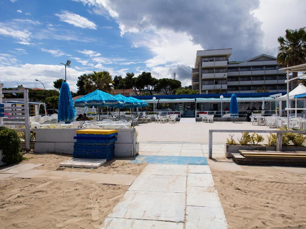 une terrasse avec des tables et des parasols bleus sur une plage dans l'établissement Manè Boutique Hotel, à Roseto degli Abruzzi