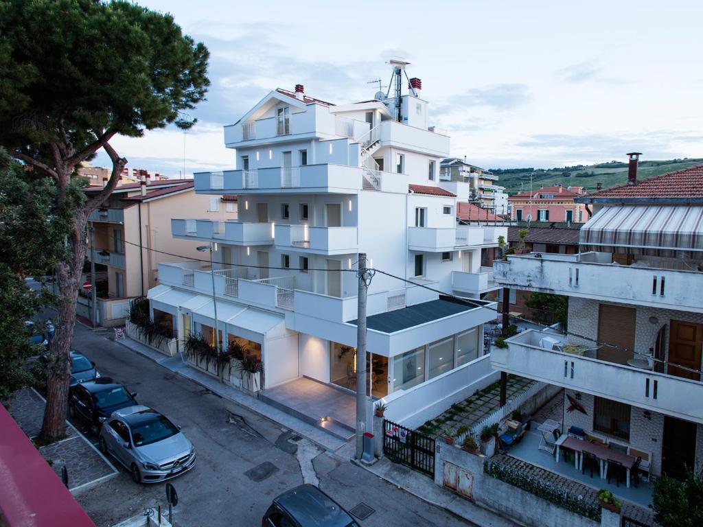 un bâtiment blanc avec des voitures garées dans un parking dans l'établissement Manè Boutique Hotel, à Roseto degli Abruzzi