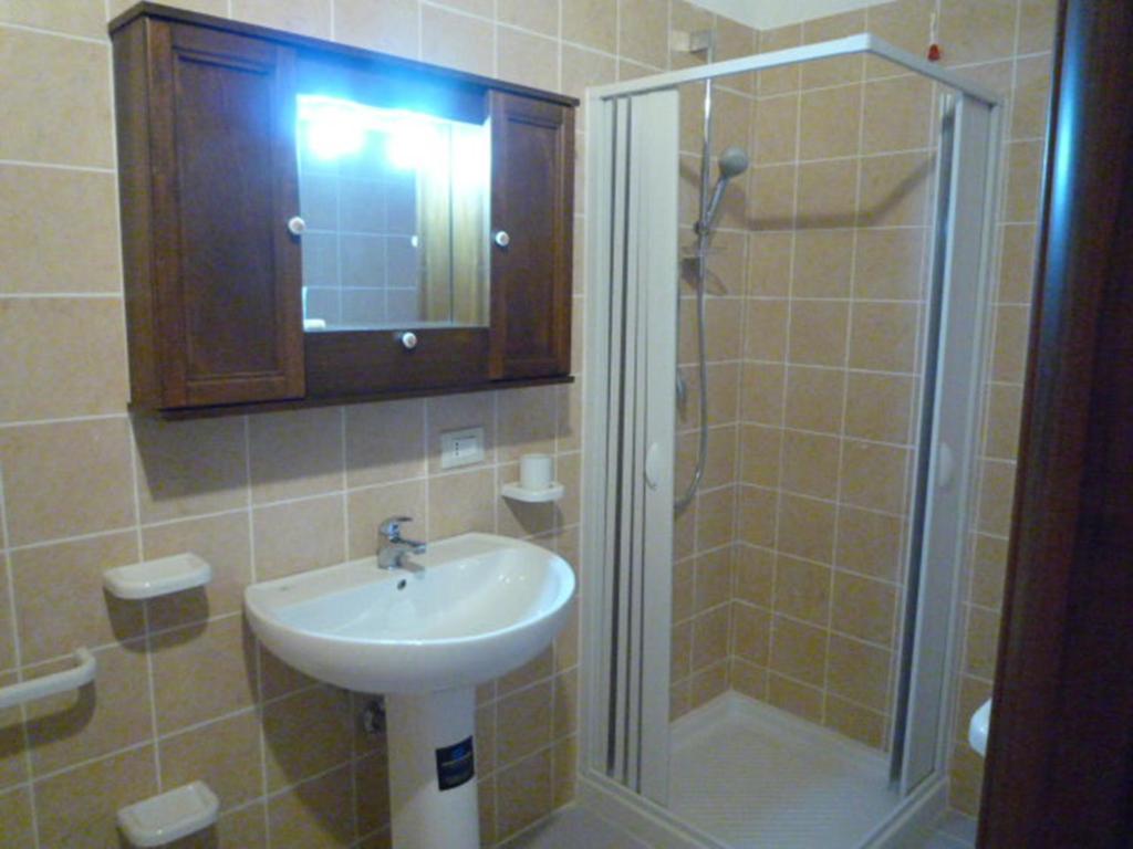 La salle de bains est pourvue d'un lavabo et d'une douche avec une porte en verre. dans l'établissement La Valle Verde hotel ristorante pizzeria, à Zambrone