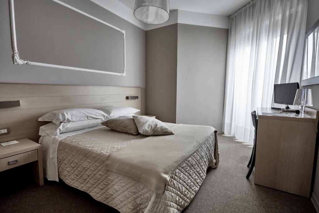 - une chambre avec un lit et un bureau avec un moniteur dans l'établissement Rouge Hotel International, à Milano Marittima
