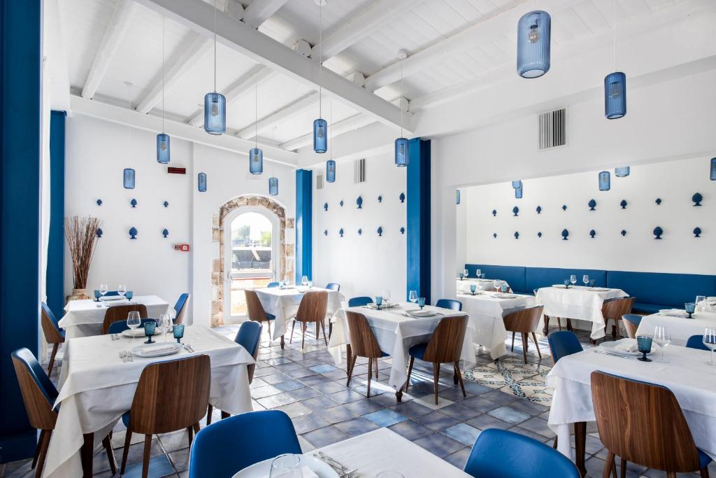 un restaurant avec des tables blanches et des chaises bleues dans l'établissement Hotel La Corte Del Sole, à Noto