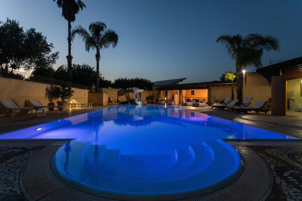 - une grande piscine bleue la nuit dans l'établissement IL FILO DI PERLE Luxury Villas, à Marsala