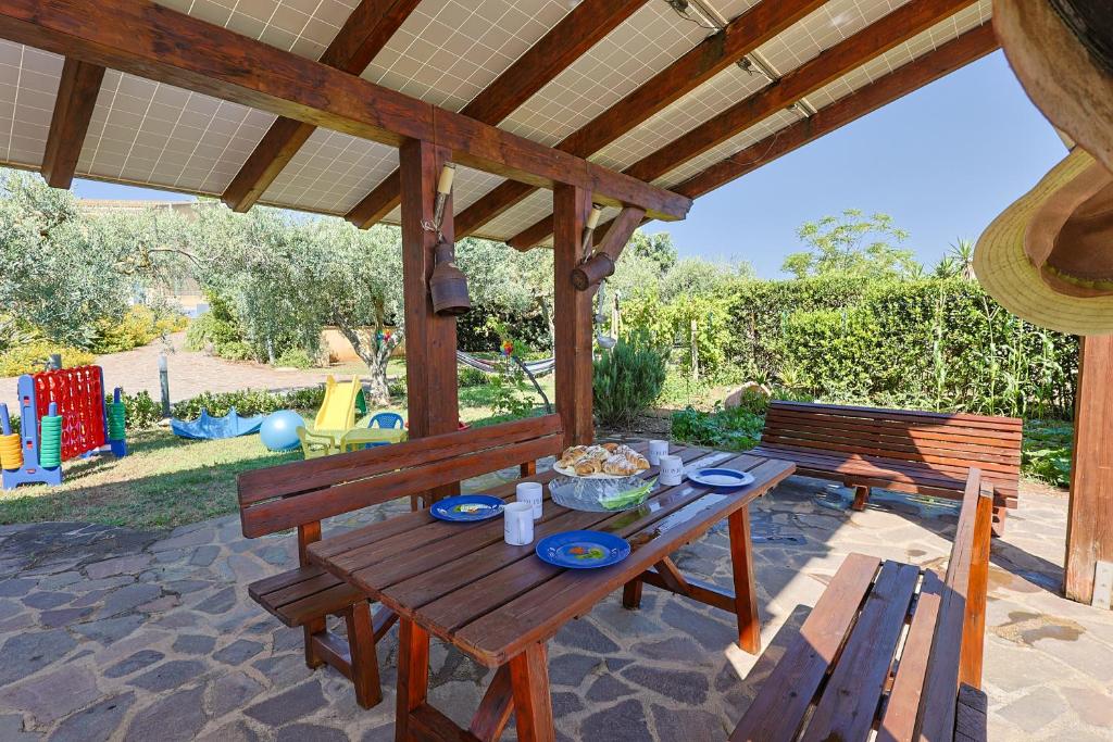 une table de pique-nique en bois sur une terrasse avec une aire de jeux dans l'établissement IL FILO DI PERLE Luxury Villas, à Marsala