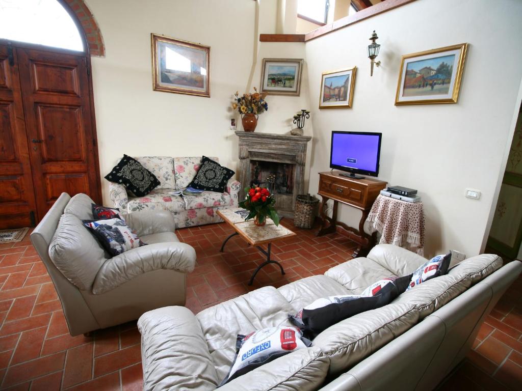 - un salon avec des canapés, une télévision et une cheminée dans l'établissement Elegant Villa in Tuscany, à Rapolano Terme