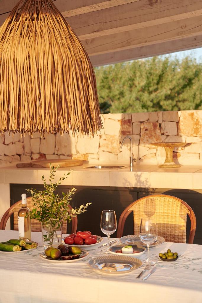 une table avec des assiettes de nourriture et des verres à vin dans l'établissement Trullo Lamatroccola, à Ceglie Messapica