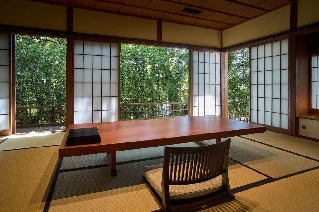 une table et une chaise dans une pièce avec des fenêtres dans l'établissement Jinya Ryokan, à Hadano