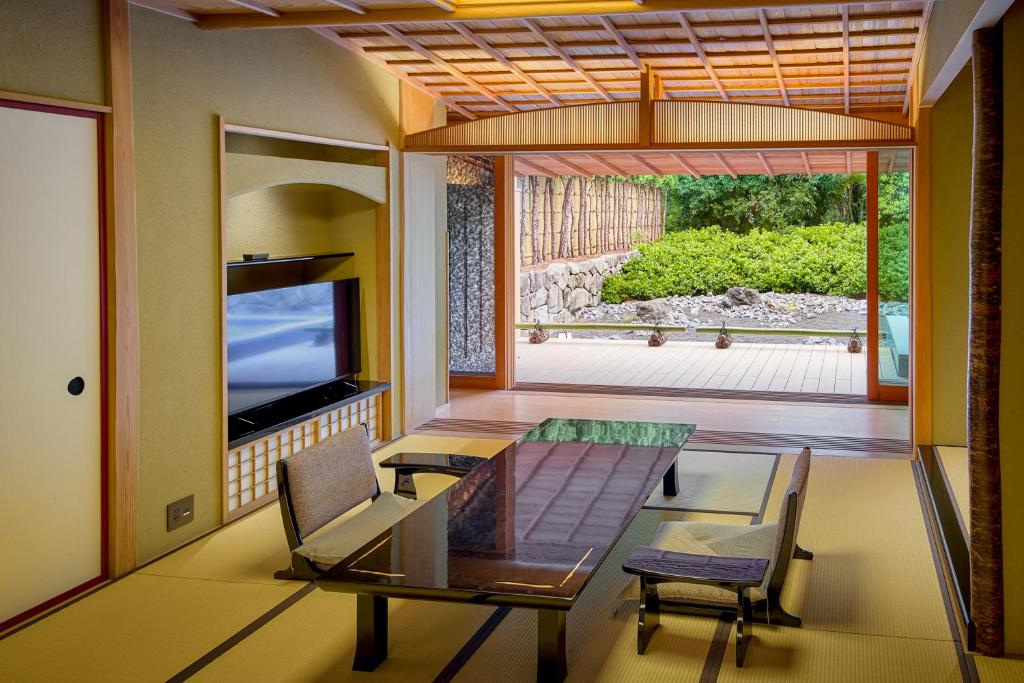 un salon avec une table en verre et une télévision dans l'établissement Akazawa Geihinkan, à Itō